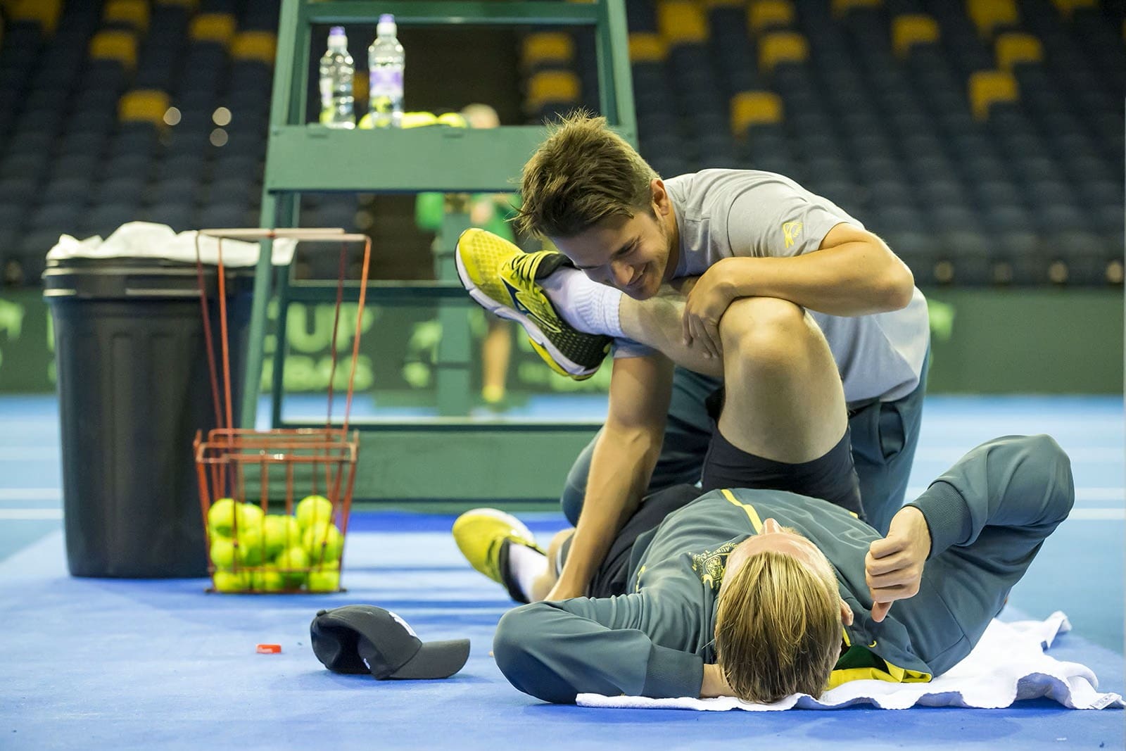 Two men practicing grappling on a mat indoors.