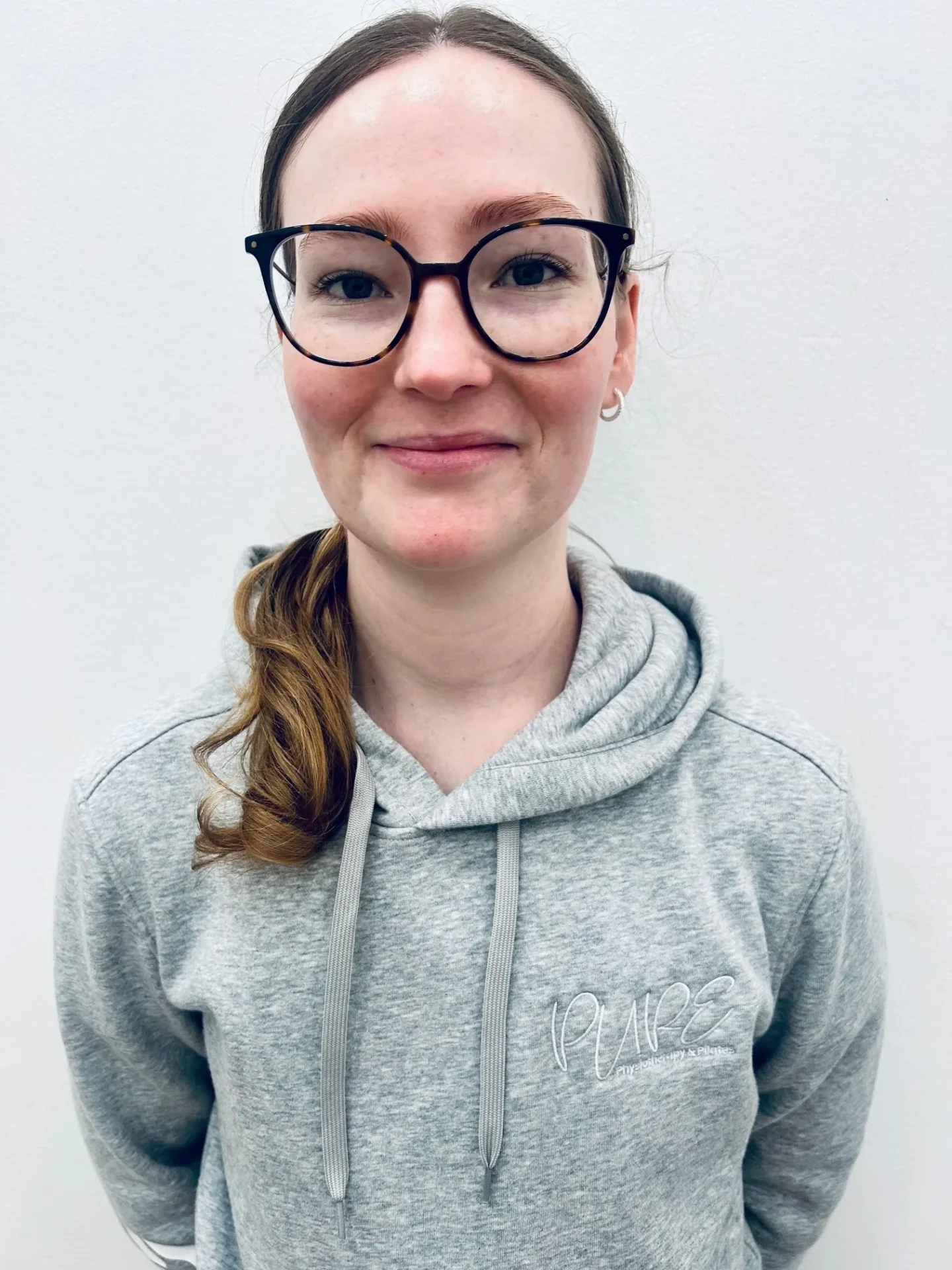 Person wearing glasses and gray hoodie smiling.